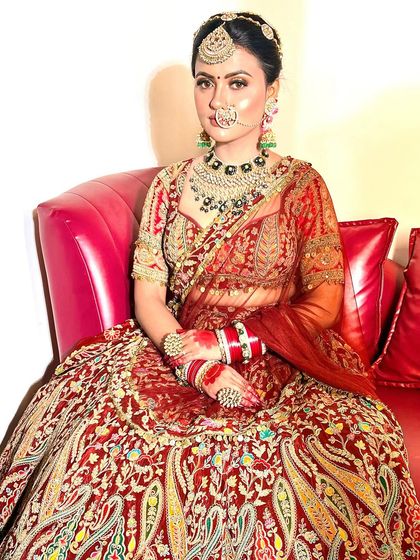 A full portrait of a bride ready for her big day. The makeup is bold and beautiful, with glittery eyes and a perfectly contoured face, matching the grandeur of her paisley-patterned lehenga.