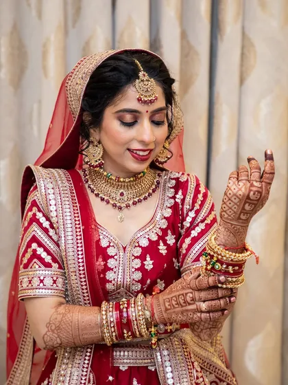 A stunning North Indian bridal look. The classic red lehenga is paired with dramatic eye makeup and a bold red lip.