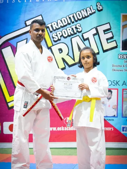 Presenting a certificate to a student who has successfully passed her yellow belt examination. Each certificate is an official recognition of their new rank and skills.