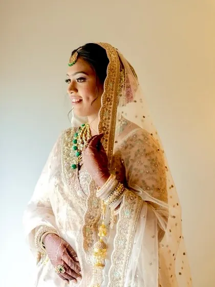 A vision in ivory and gold. The bride's radiant makeup and soft smile are framed beautifully by her dupatta.