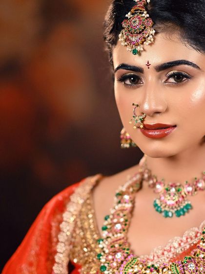 A close-up bridal shot focusing on the makeup and jewelry. The lighting is carefully placed to highlight the maang tikka and the glossy lip, making it a great shot for a makeup artist's portfolio.