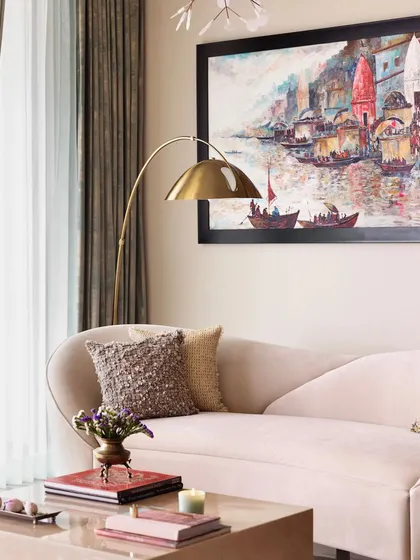 A close-up of the blush sofa, highlighting the textured pillows and the brass floor lamp that adds a touch of modern glamour.