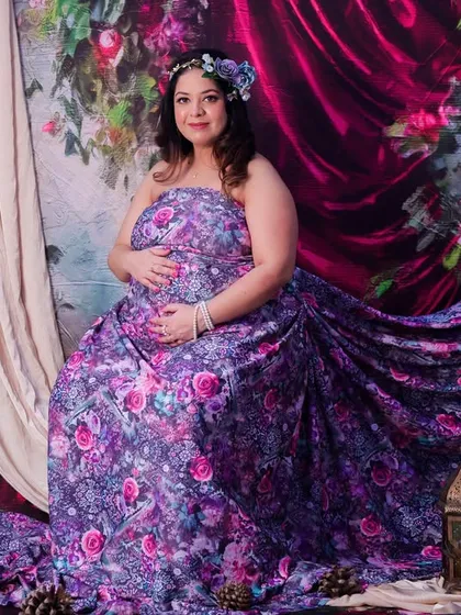 A fairytale moment brought to life in our studio. This mom-to-be looks absolutely radiant in a flowing floral gown, set against a romantic, painterly backdrop that creates a truly magical portrait.