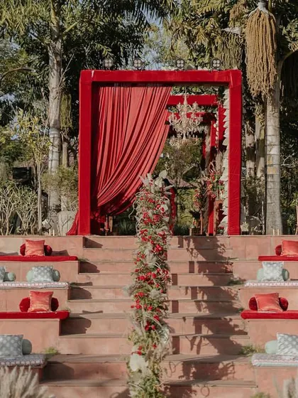 The groom's entrance for the 'Regal Rustic Reverie' wedding. The dramatic red drapes and floral archway created a regal and impactful start to the ceremony.