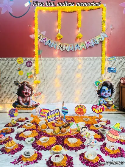 This Krishna-themed Annaprashan setup is perfect for celebrating your little Kanha. The decor features cutouts of Baal Gopal, marigold garlands, and a beautiful floral arrangement on the floor where the ceremonial food is placed.