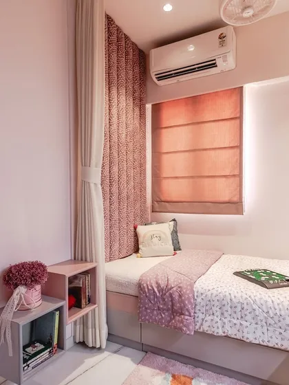 A wider view of the compact pink room, showing the daybed setup with a custom headboard and roman blinds. The use of a curtain can partition the sleeping area, creating a cozy nook that feels private and secure.