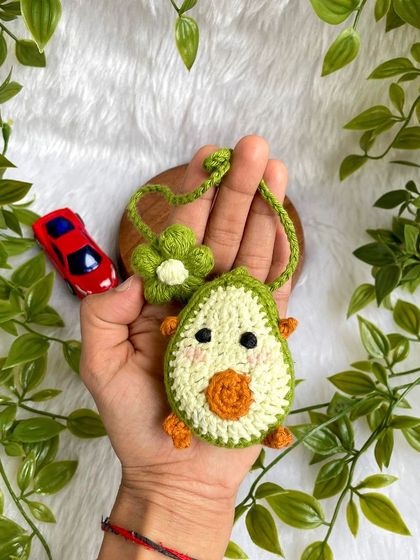Holding the avocado car charm.