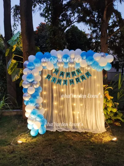 A simple and elegant balloon arch with a fairy light curtain, set up outdoors in a garden. This is perfect for an evening celebration.
