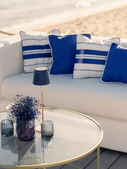 A detail shot of the comfortable seating, highlighting the nautical-themed cushions and a small lamp, perfect for the transition to evening.