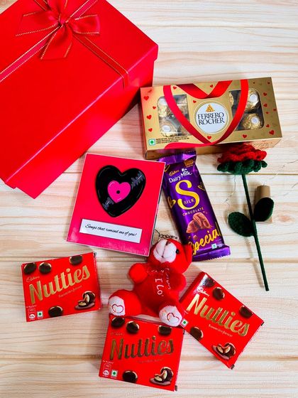 A classic red-themed love hamper. This gift set includes chocolates, a teddy bear, a handmade rose, and a Spotify slider card that plays your special song.