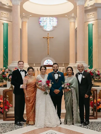 For this beautiful Catholic wedding ceremony, we created a look of timeless elegance for the entire family. The groom stands distinguished in a deep teal tuxedo, a perfect complement to the bride's classic white gown. We balanced the frame with the mothers in sage green and rusty rose gold, creating a family portrait that is warm, sophisticated, and perfectly in sync.