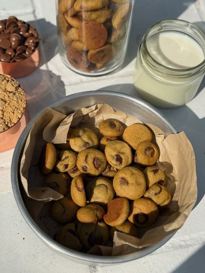 A top-down view of my mini chocolate chip cookies in a bowl, surrounded by the ingredients I use. They are bite-sized, perfectly baked, and packed with warmth in every crunch.
