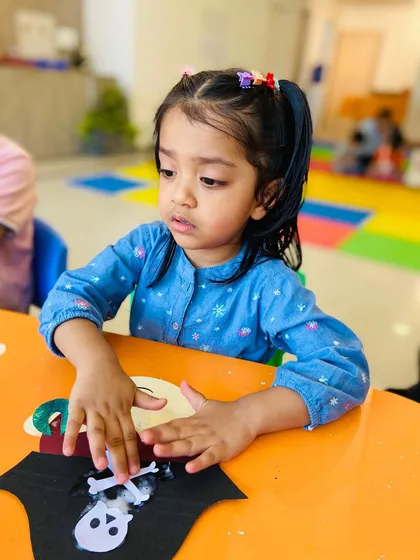 This girl is focused on adding details to her pirate hat craft.