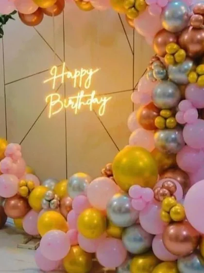 A beautiful balloon crescent arrangement in shades of pink, gold, and silver, with a neon sign, perfect for a stylish celebration.