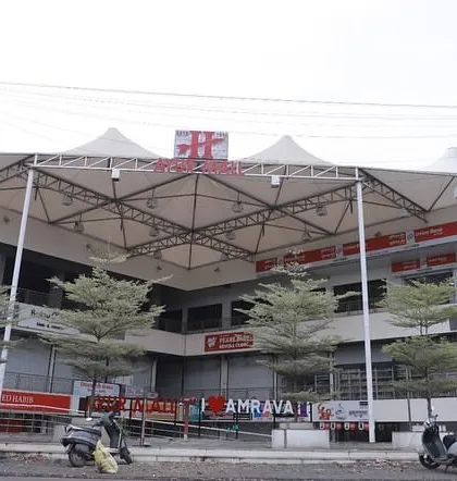 A street-level view of the completed Ayur Mall, showing the prominent tensile roof structure that covers the central atrium. This architectural element provides shelter while allowing natural light, creating a bright and welcoming food court and plaza area.