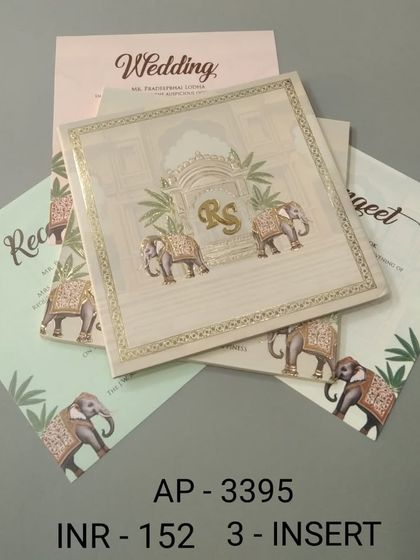 A simple yet regal invitation in a cream color, featuring two elephants and a custom 'RS' monogram. This set includes three inserts for your Reception, Sangeet, and Wedding details.