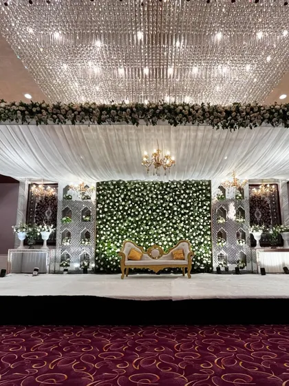 We specialize in creating serene and elegant setups for Nikaah and Walima ceremonies. This stage features a stunning wall of white and green florals, complemented by intricate latticework panels and magnificent crystal chandeliers for a truly royal feel.