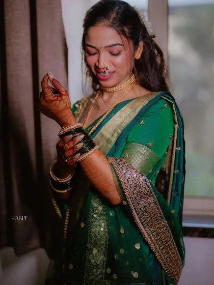 Adjusting her bangles, this bride shows off her complete engagement look, with a beautiful green saree and half-up, half-down hairstyle.