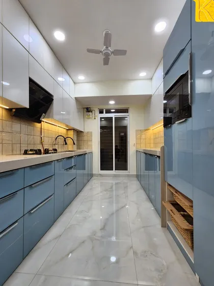 This is a parallel modular kitchen we designed for maximum efficiency and style. It features high-gloss acrylic finish cabinets in a calming powder blue and white, handleless drawers for a clean look, and integrated space for appliances, showcasing our ability to create functional yet beautiful kitchen layouts.
