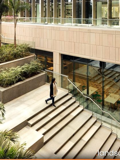 The landscape design for Zydus Headquarters includes multi-level terraced courts that echo traditional Indian stepwells. These spaces provide shaded public areas for employees, with integrated planters and palm trees that enhance the connection to nature within the corporate environment.