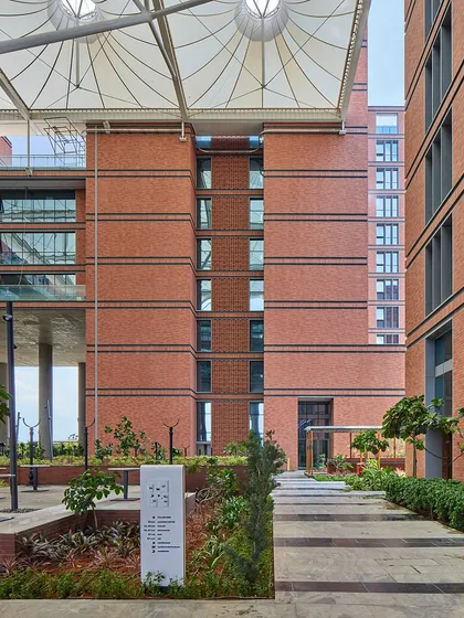 A view of the Wipro Hyderabad campus showing the tensile canopy structure that provides shade over the central plaza. This lightweight structure creates comfortable semi-outdoor spaces for cafes and kiosks, animating the heart of the campus.