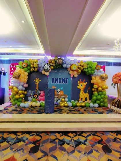 A wider view of the jungle-themed party hall. You can see how the main stage backdrop, floral arrangements, and themed decor elements come together to transform the entire space into a cohesive and festive environment.