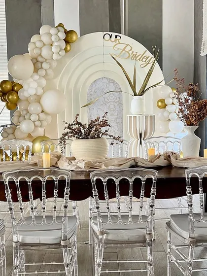 A closer look at the elegant boho bridal shower we styled for Kavya. The decor features a neutral palette with white and gold balloons, dried floral arrangements, and clear ghost chairs for a sophisticated look.