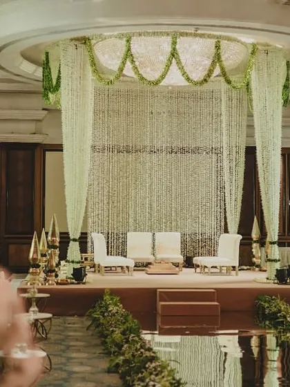 A closer look at the stage, where the sheer curtain of flowers and traditional brass lamps create a divine setting for the ceremony.
