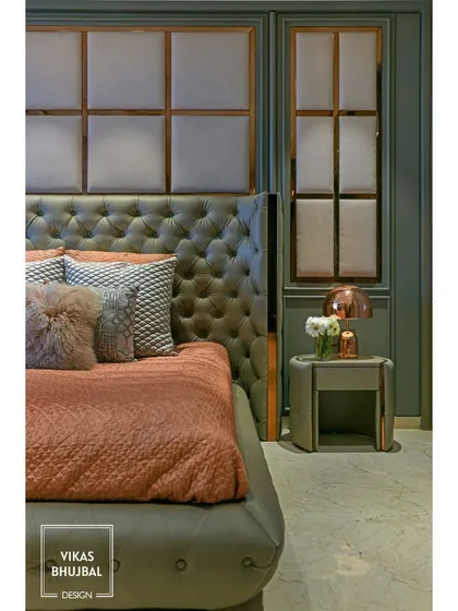 We used a classic combination of sage green and dusty rose in this elegant bedroom. The tall, button-tufted headboard and paneled walls with metallic trim add a touch of timeless glamour.