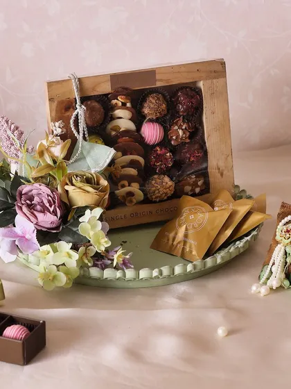 The Blooming Beauty Rakhi Hamper features a beautiful chocolate platter, cookies, and a Rakhi & Loomba set.