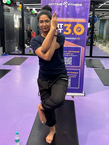 A participant in the Eagle Pose, showcasing the focus required for balancing asanas. Our instructors provide guidance to help everyone achieve their best form.