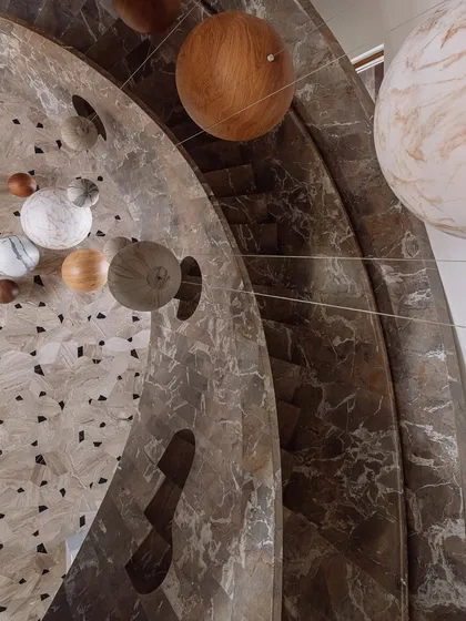 Details are where the story lives. This sculptural staircase is more than just a way to move between floors; it's a celestial experience, with an installation of wooden and marble spheres that hang like a confetti carnival within the marble-clad stairwell.
