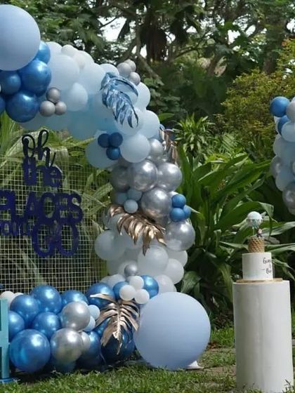 An outdoor hot air balloon themed setup for a first birthday. This party features a large balloon arch and a custom hot air balloon prop made of balloons, perfect for a garden celebration.