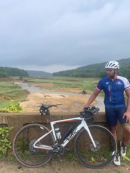 A rider and his bike against the backdrop of a muddy river during the Jog Falls 1000K BRM. The monsoon season brings its own unique beauty and challenges to the ride.