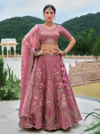 A stunning dusty rose lehenga featuring unique architectural and floral embroidery. The color is sophisticated and the craftsmanship is exquisite, making it perfect for an engagement.