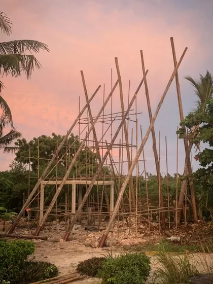 The early stages of the spa construction at Kizikula. The scaffolding, made from local timber, creates a beautiful, sculptural form against the sunset sky, hinting at the A-frame structure to come.