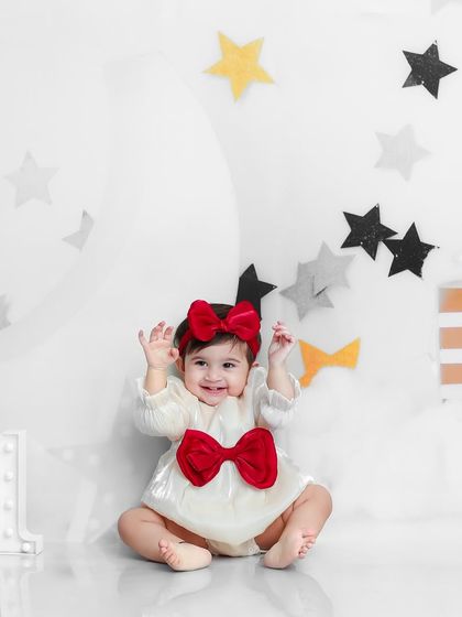 A star is born. This little one is celebrating her first birthday with a "Moon and Stars" theme, looking adorable in her white and red outfit.