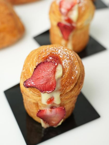 Say hello to the cruffin, a delightful hybrid of a croissant and a muffin. This image shows a strawberry-filled cruffin, a trendy and delicious pastry we teach.