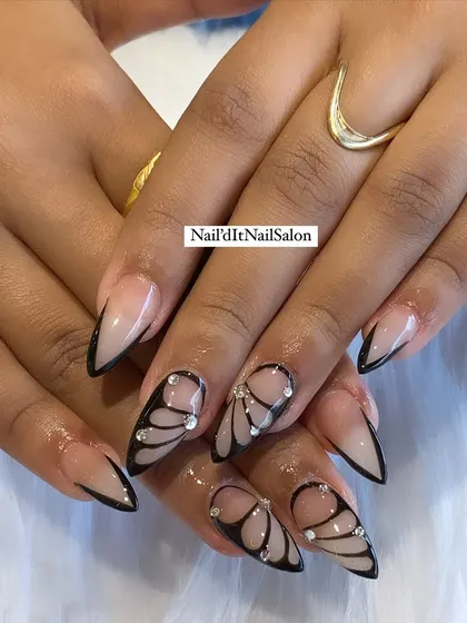 A creative butterfly wing design using abstract lines. This set combines a sharp, black V-shaped French tip with delicate, hand-painted butterfly wings on accent nails, dotted with tiny crystals.