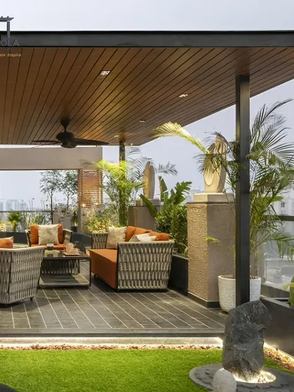 This beautiful balcony extension features a solid roof with a fan and lush planters. It effectively transforms an open balcony into a comfortable, semi-enclosed outdoor lounge with a city view.