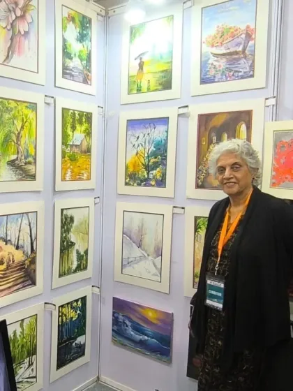 A wall full of beautiful art! Harinder ma'am stands next to a display of her numerous landscape and nature paintings at the art exhibition.