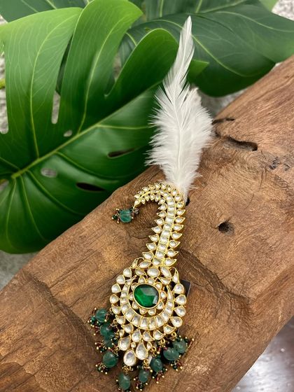 A touch of drama and royalty. This turban accessory, or sarpech, features a kundan peacock design with green beads and a striking white feather.