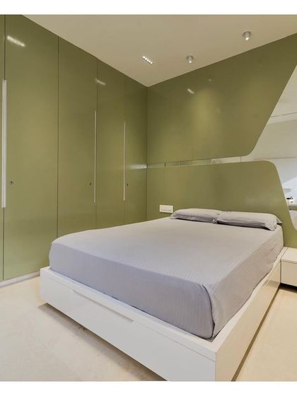 In the parent's bedroom, a punch of olive green on the wardrobes and headboard creates a calming, nature-inspired atmosphere. A large, custom-shaped mirror was used to visually expand the compact room and enhance the sense of space.
