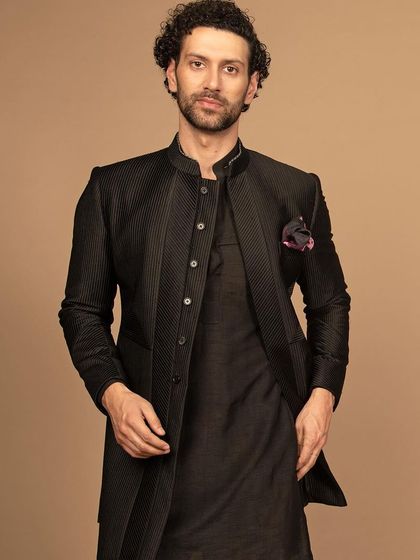 A sleek, black Indo-Western ensemble. The structured jacket paired with a kurta offers a sophisticated look that is perfect for evening events, combining modern tailoring with traditional roots.