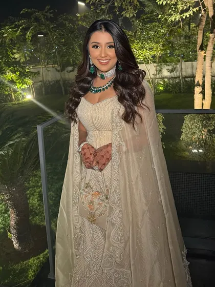 A full view of Urvi's glamorous look, complete with a beautiful cape and stunning emerald jewelry. The makeup is designed to be equally show-stopping.