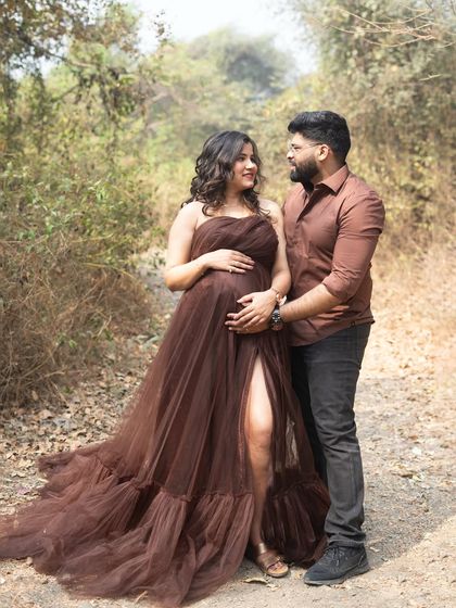 A loving glance between partners during an outdoor maternity shoot. The earthy tones of their outfits blend beautifully with the natural, wooded surroundings.