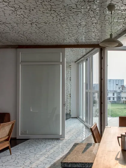 The residence area on the top floor of the Artrovert studio. The flooring, made of broken ceramic tiles, adds texture and character, while large windows connect the living space to the terrace and the city beyond.