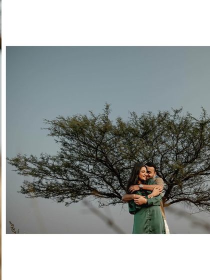 A wide shot of the couple embracing under a large, sprawling tree. The composition creates a beautiful silhouette effect and a sense of being sheltered by nature.