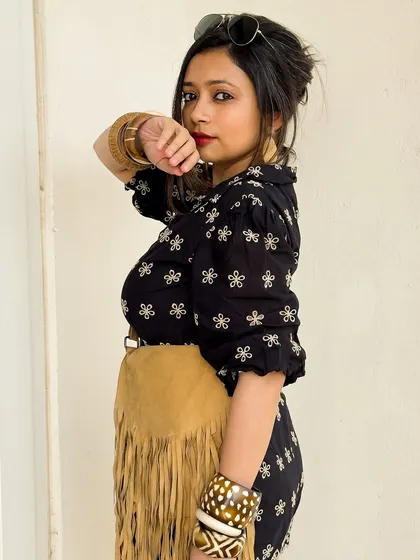 A side profile of the black boho romper look. The red lip adds a pop of color and confidence.