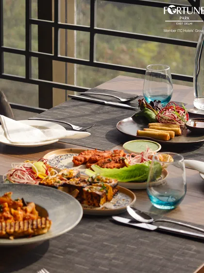 A table at Zodiac laden with a variety of our culinary offerings, from pasta and grilled items to traditional Indian dishes, showcasing the breadth of our menu.